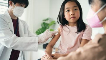 little girl looking at her mother while getting vaccinated
