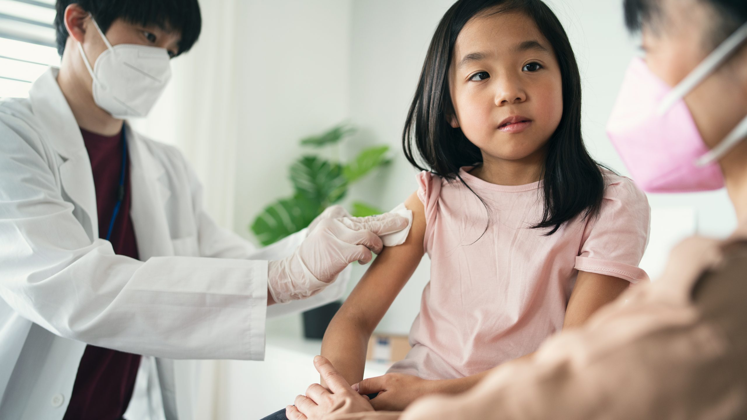 little girl looking at her mother while getting vaccinated