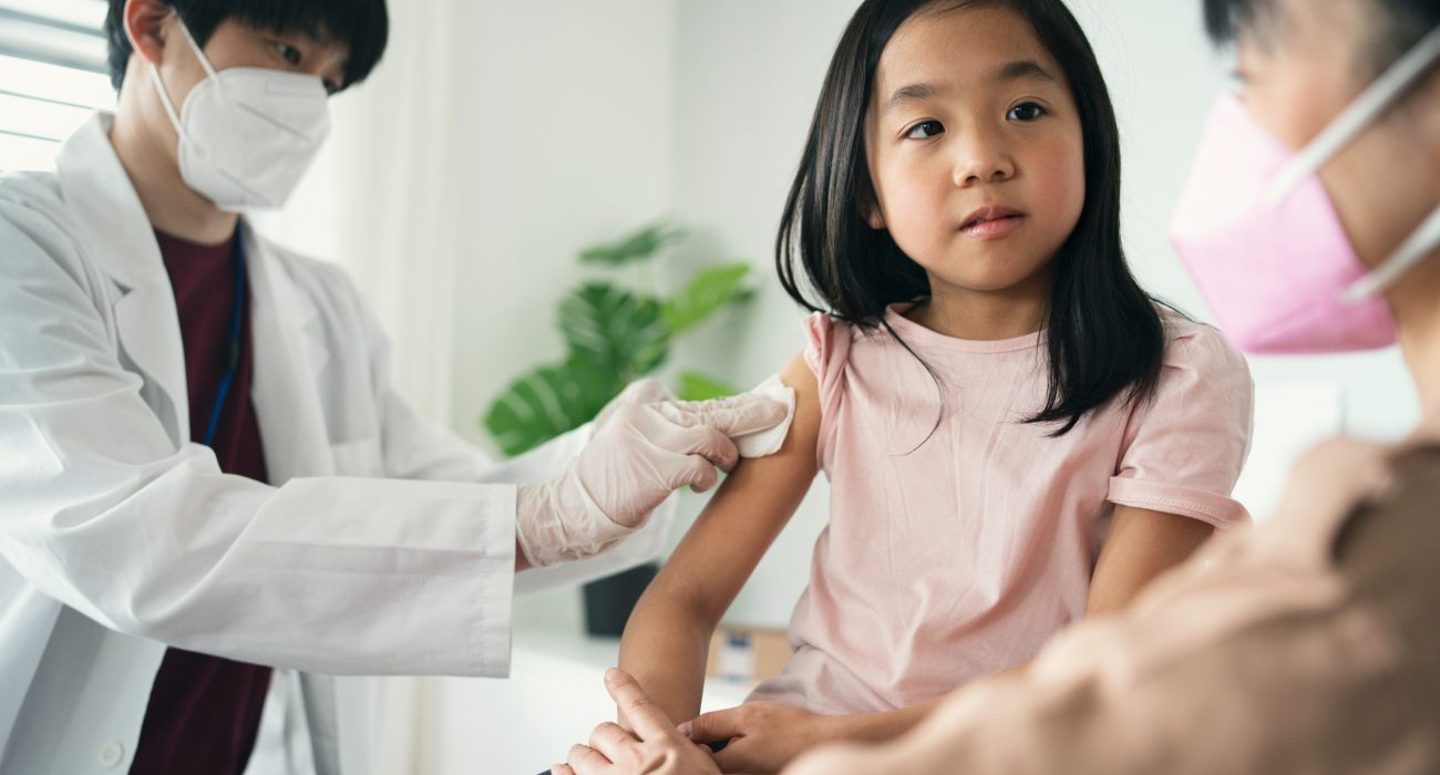 little girl looking at her mother while getting vaccinated